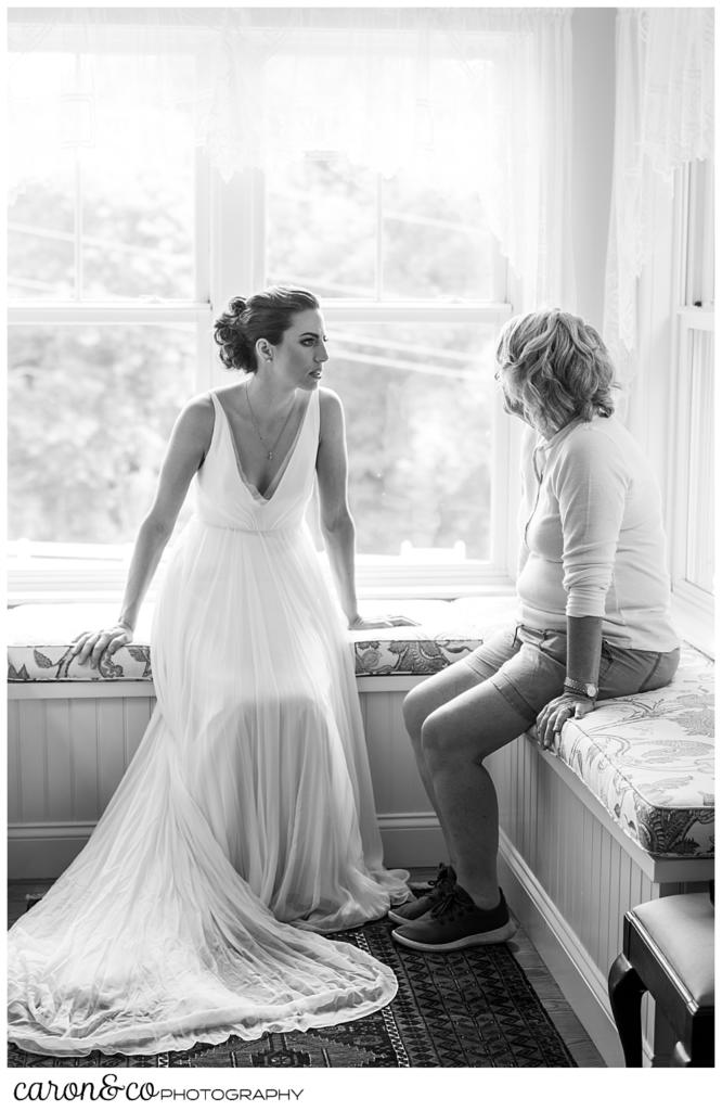 black and white photo of a bride in a sleeveless white dress, and her mother sitting on window seats