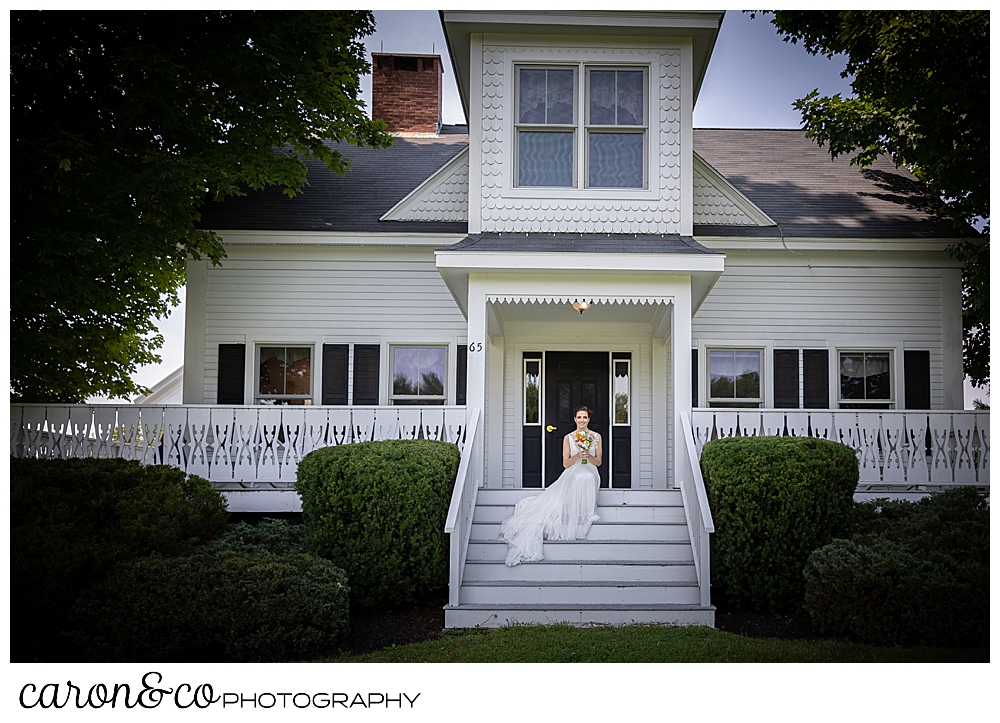 a bride wearing a sleeveless white dress, sits on the front steps of a White House with black trim