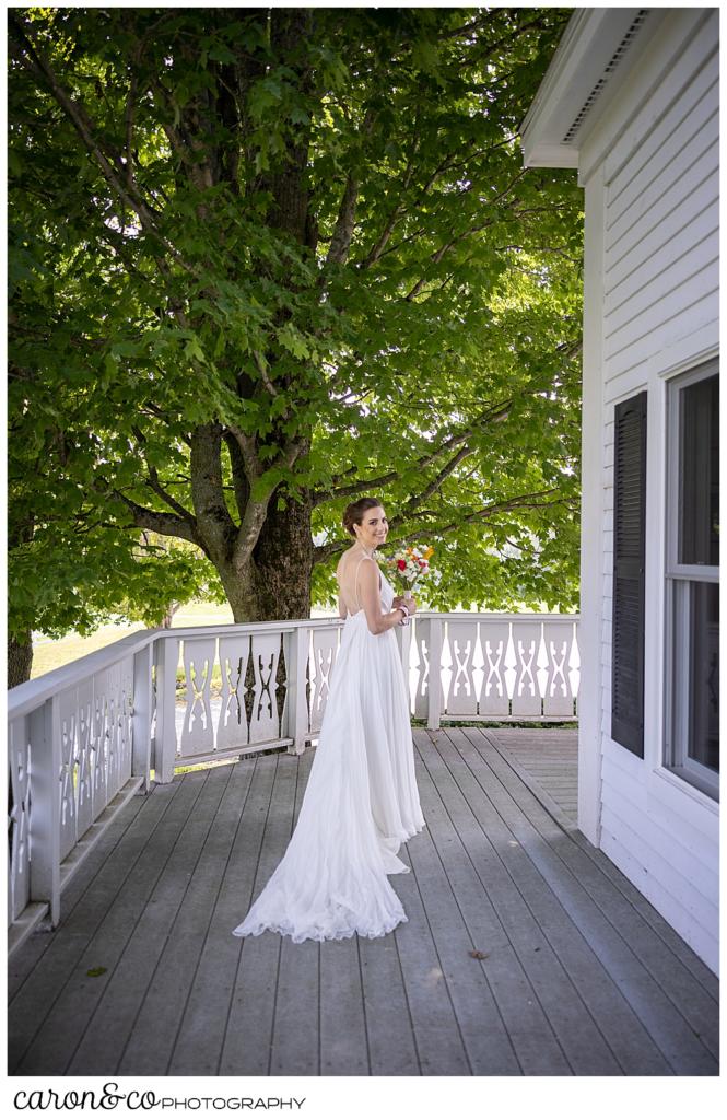 a bride walks on a front porch, looking back at the photographer