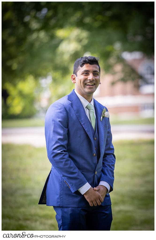 a groom in a blue suit, turns to see his bride during their Maine wedding day first look