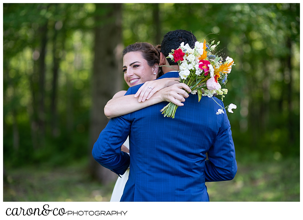 a bride with a bright bouquet, hugs her groom