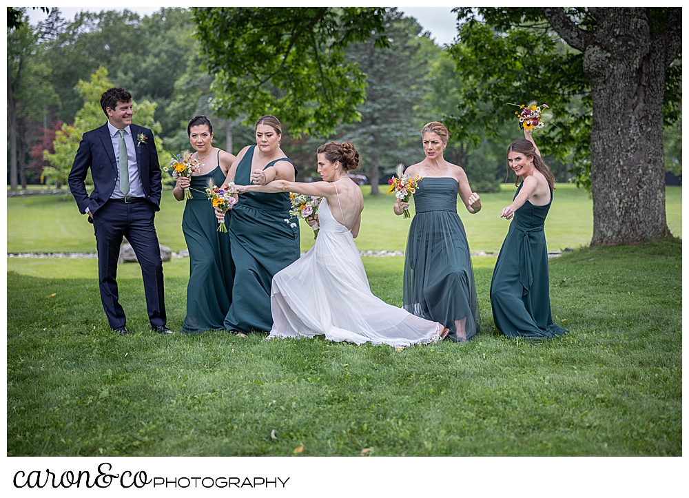 a bride strikes a pose with her 4 bridesmaids, and bridesman