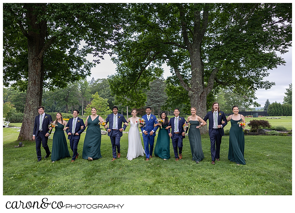 a bridal party with linked arms, walks on the Pineland Farms campus, at a joyful Pineland Farms wedding day