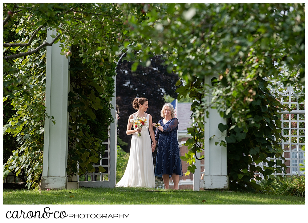 a bride and her mother pause before they enter the Pineland Farms Garden, at a joyful Pineland farms wedding