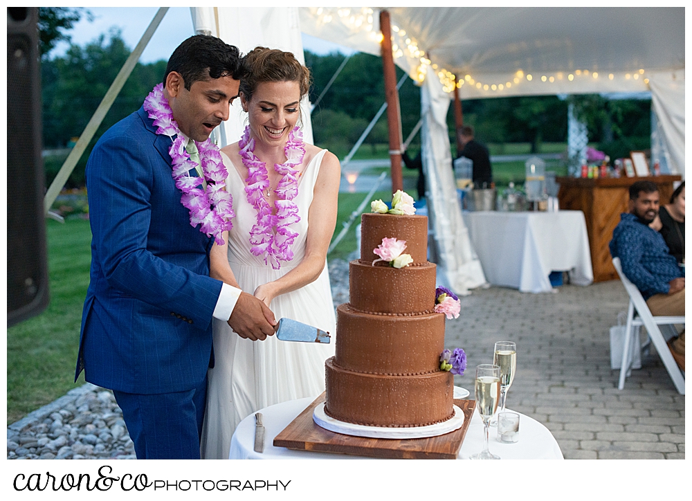 a bride and groom cut a four tiered chocolate wedding cake