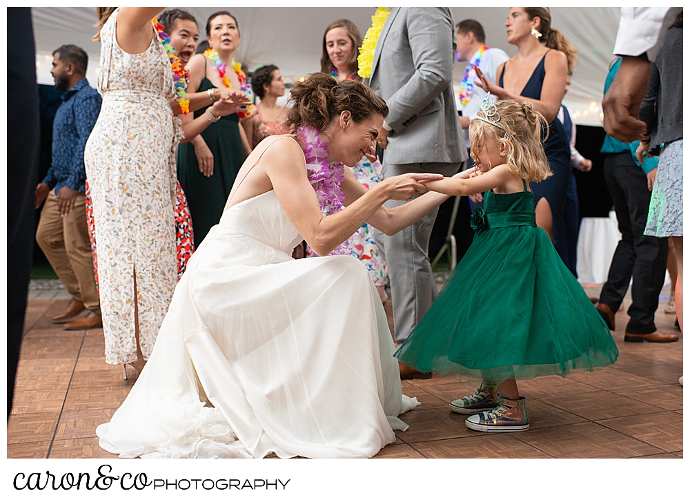 a bride scotching down to dance with a flower girl at a tented Pineland farms wedding