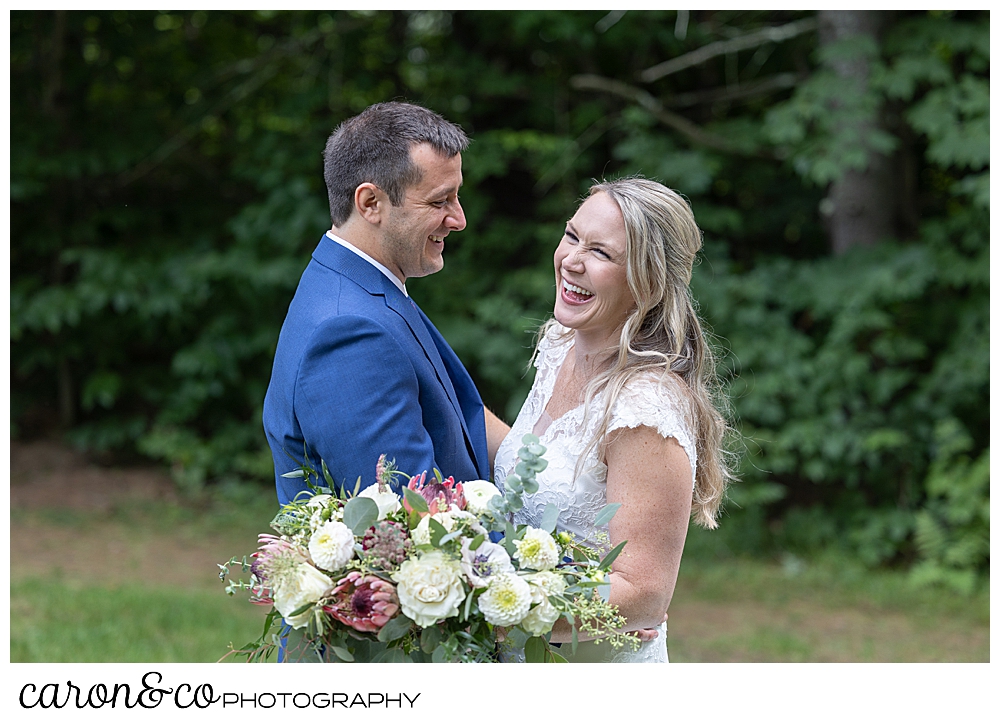 a bride and groom standing together, they're smiling during their wedding day first look at Kingsley Pines, Raymond, Maine