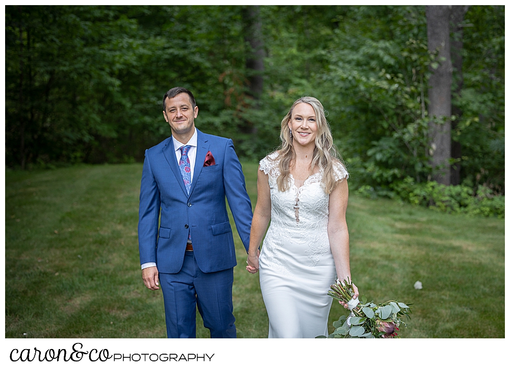 a bride and groom are walking hand in hand in a grassy field