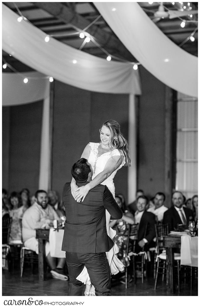 black and white photo of a groom lifting his bride during their first dance