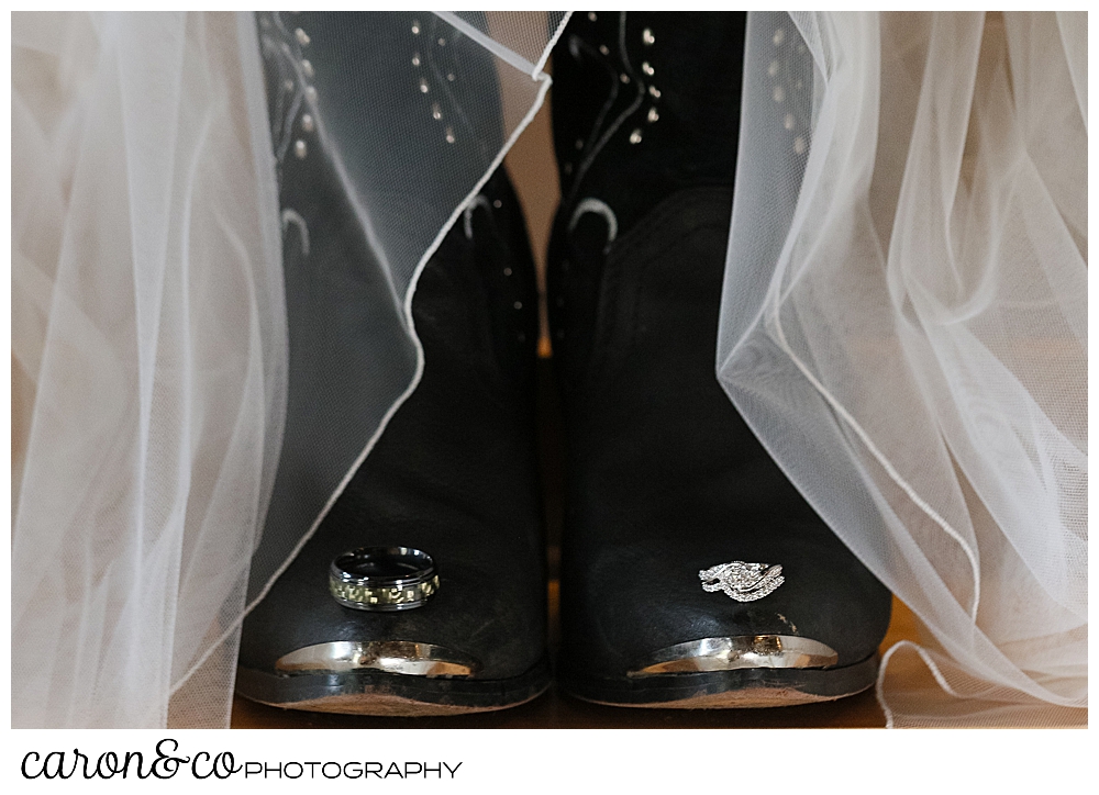 bridal details of black cowboy boots, a tulle wedding veil, and two wedding bands