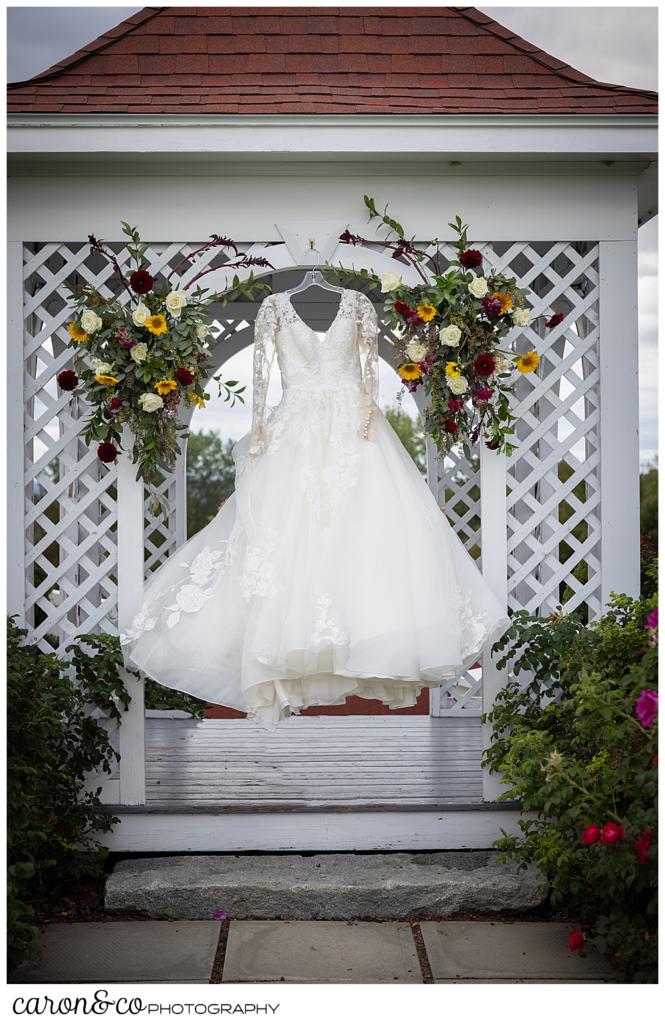 a wedding dress hangs from a small gazebo