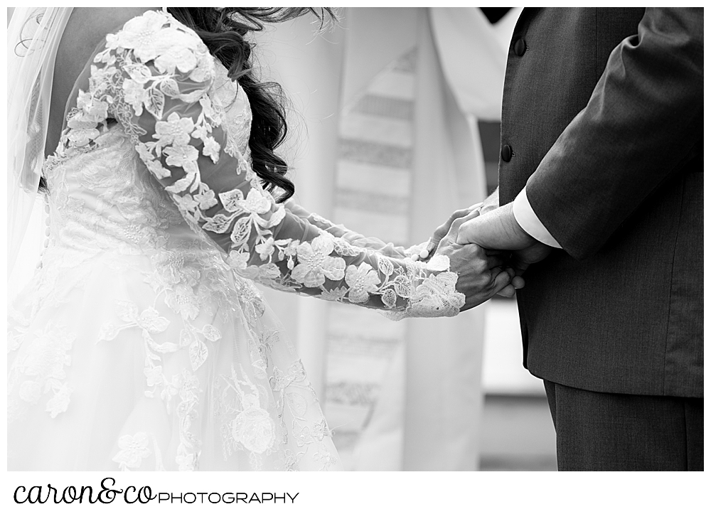 black and white photo of a bride and groom holding hands during their wedding at Maine wedding Barn