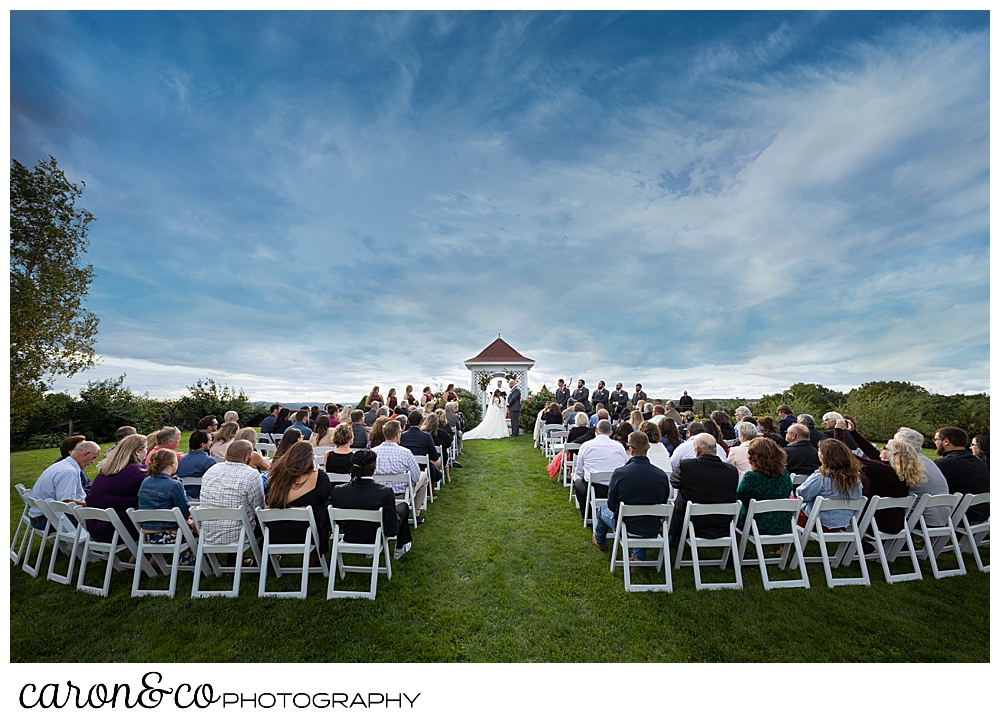 a wide photo of an outdoor wedding ceremony at The Maine wedding Barn in Minot Maine
