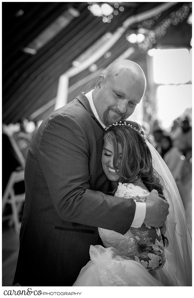 black and white photo of a groom hugging his bride as they dance their first dance at a wedding at Maine wedding barn in Minot Maine