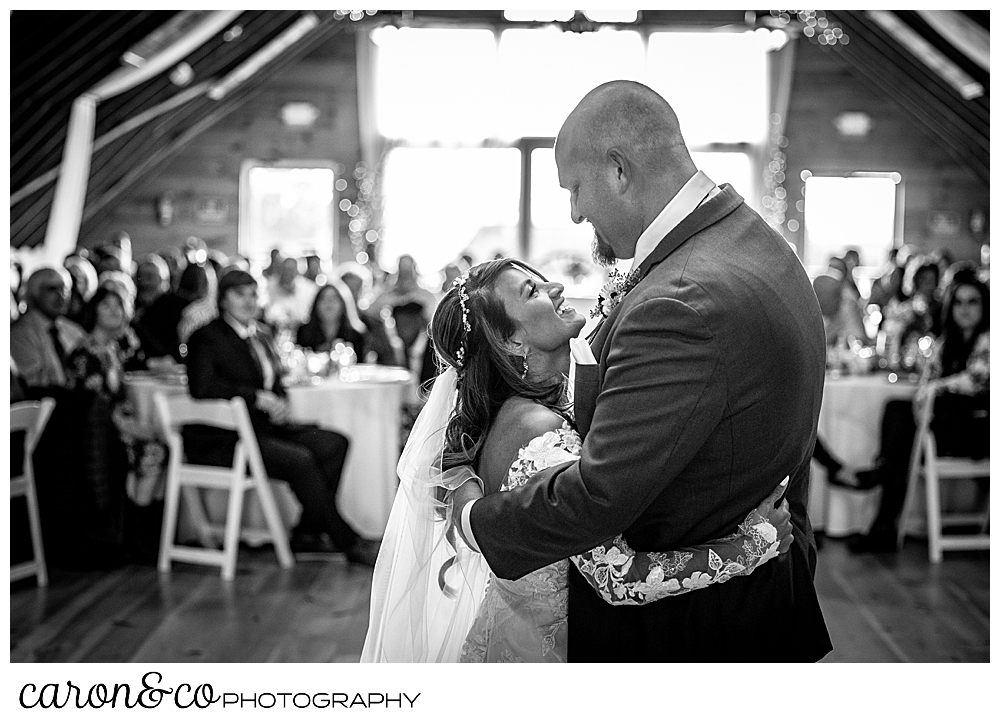 black and white photo of a bride smiling up at her groom during their first dance at a wedding at Maine wedding barn in Minot Maine