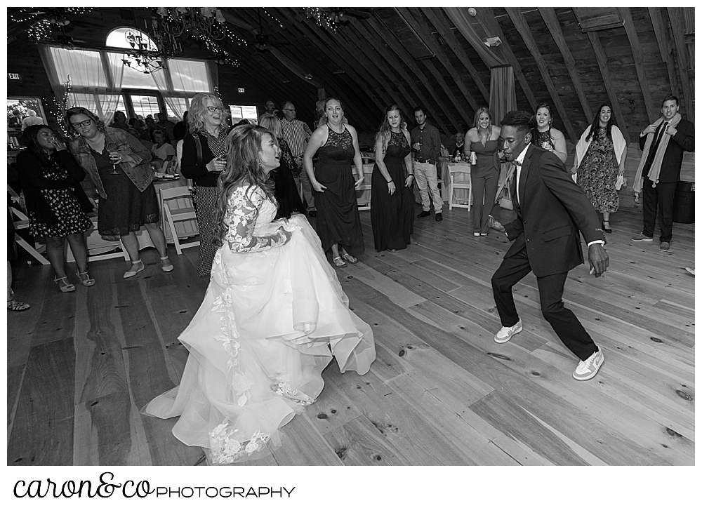 black and white photo of a bride dancing during with a guest a wedding at Maine wedding barn in Minot Maine