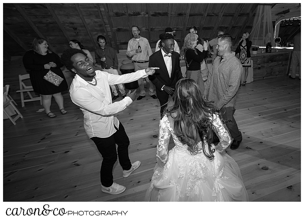 black and white photo of a bride dancing with her brothers at a wedding at maine wedding barn in minot maine