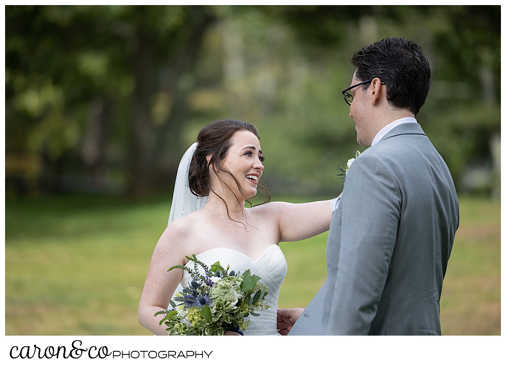 a smiling bride, wearing white, throw an arm out to her groom during their wedding day first look