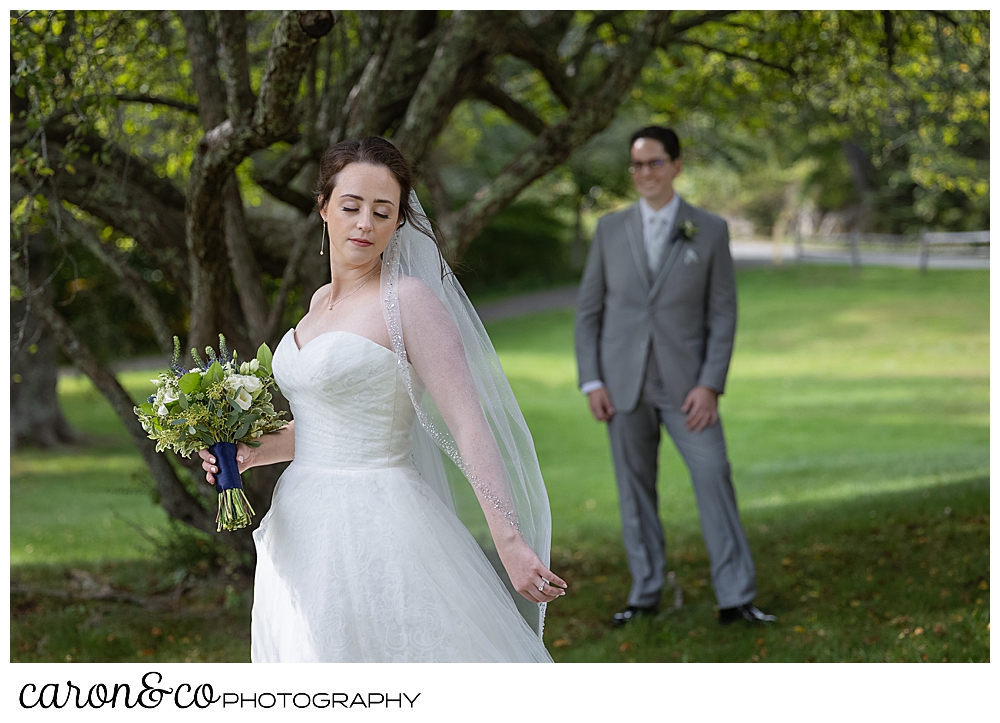 as a bride poses for the camera, her groom stands behind and watches