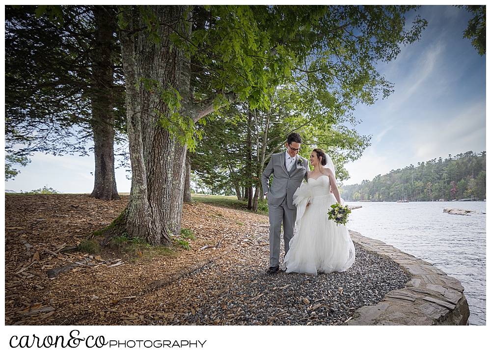 a bride and groom walk along the water at Barrett Park, Boothbay Harbor, Maine