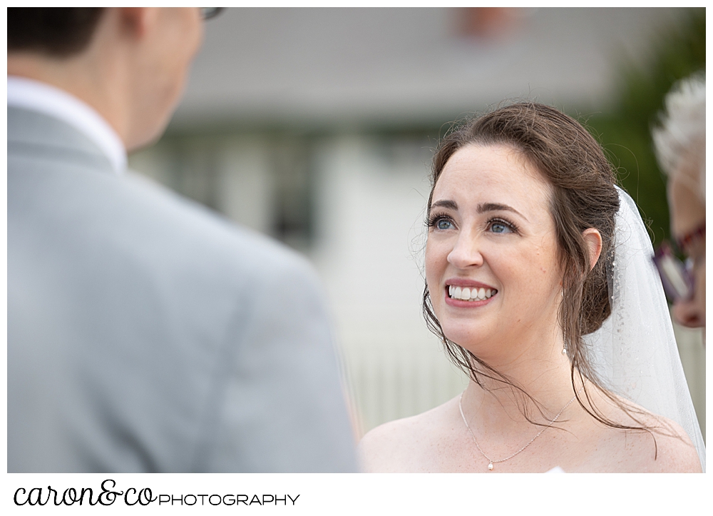 a bride smiles at her groom during an outdoor ceremony