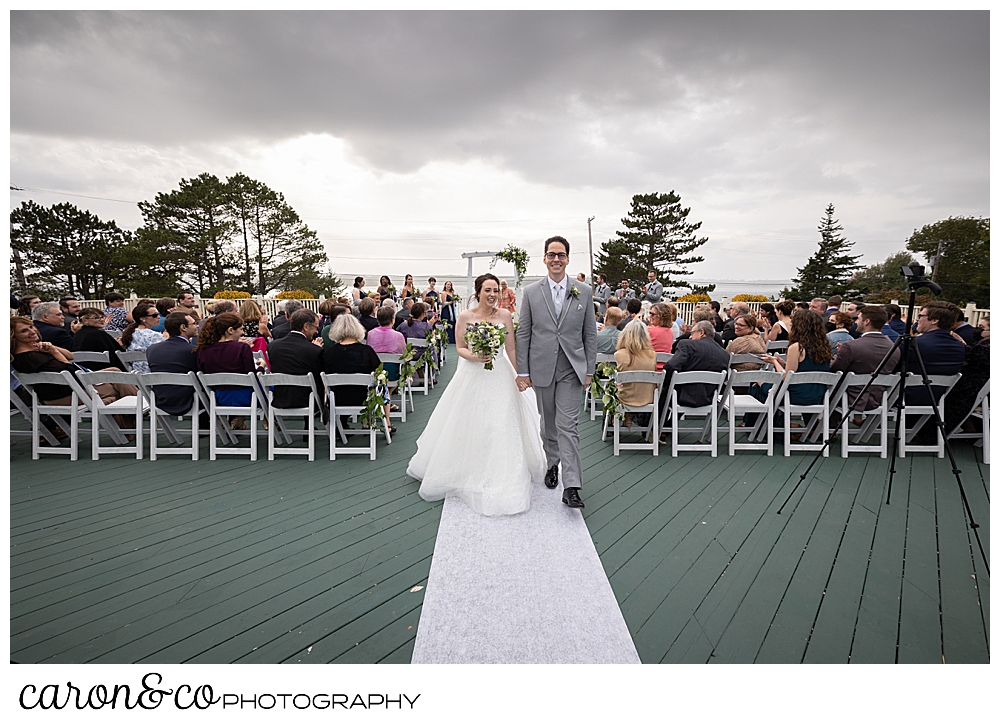 a bride and groom at the end of their recessional at their outdoor Spruce Point Inn Maine wedding ceremony, Boothbay Harbor, Maine