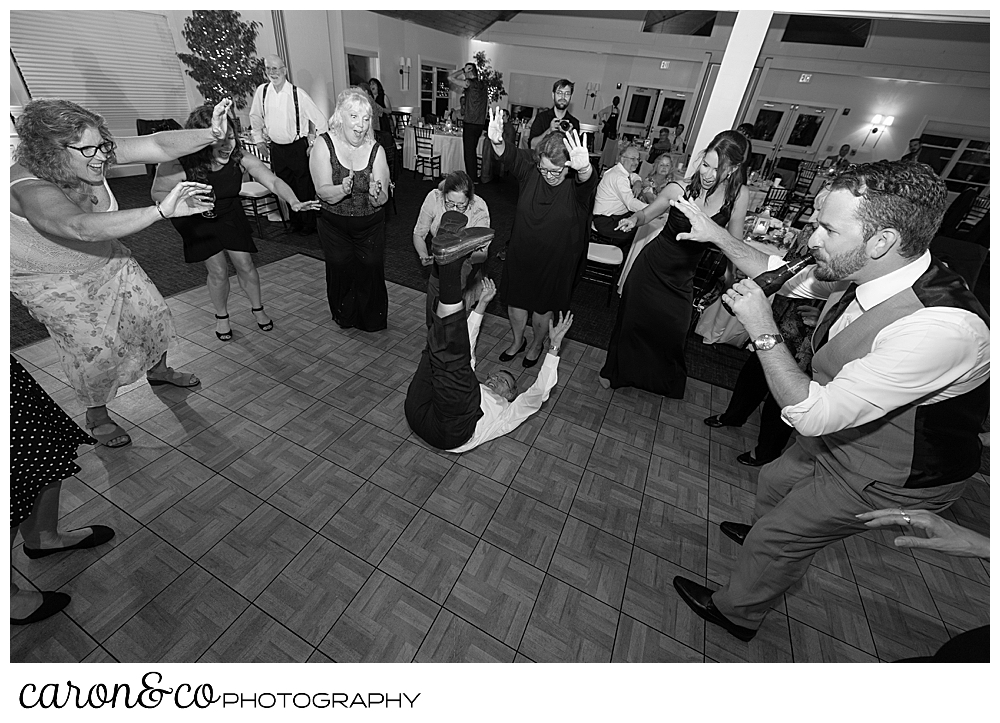 black and white photo of a wedding guest dancing while laying on the floor during a wedding reception