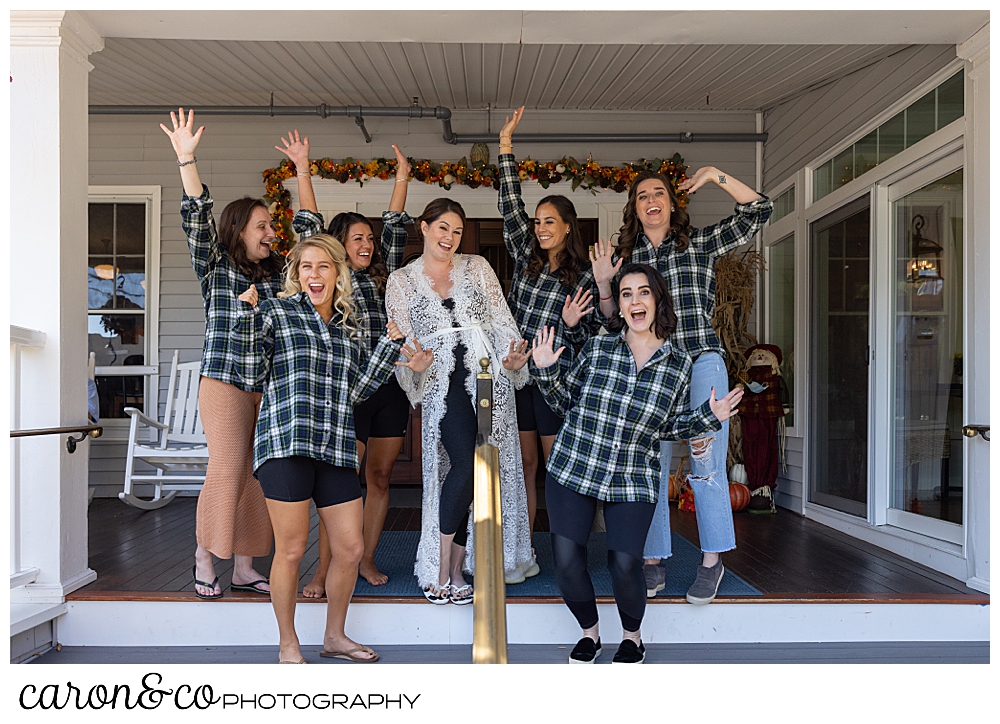a bride wearing a white lacy robe, is surrounded by her bridesmaids wearing plaid shirts, as they cheer on the front porch of the Nonantum Resort, Kennebunkport, Maine