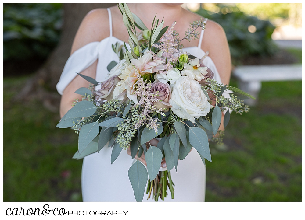 a bridal bouquet of pink and cream flowers, with lots of green leaves