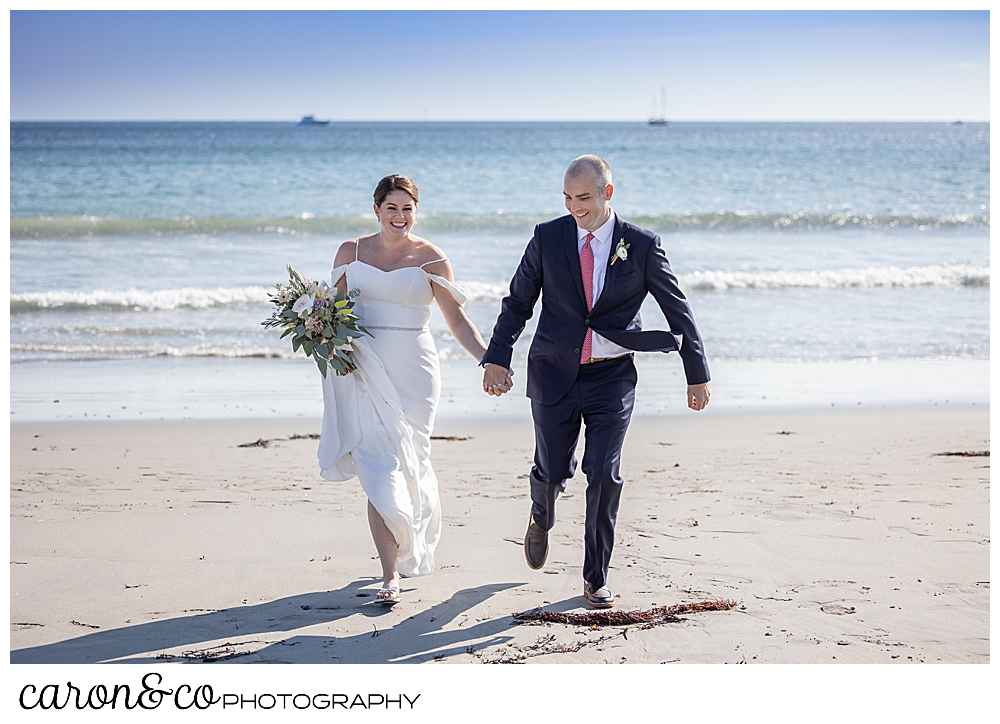 a bride and groom hold hands and run on Gooch's Beach, Kennebunk, Maine