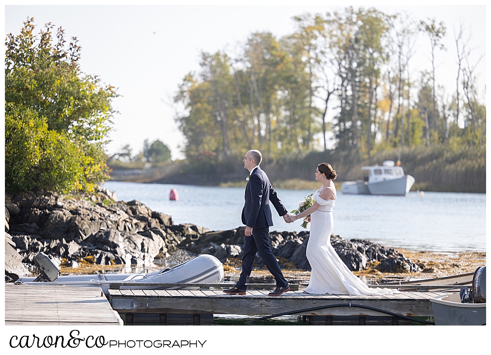 a bride and groom hold hands and walk on the dock at The Nonantum Resort, Kennebunkport, Maine