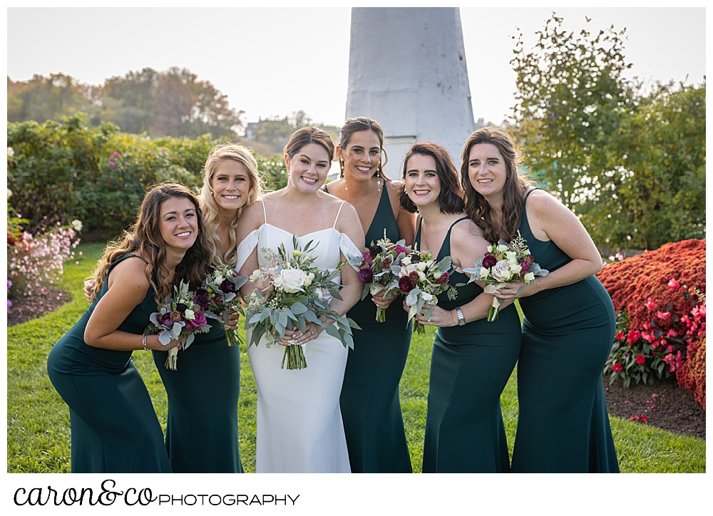 a bride wearing a white dress, is surrounded bu her bridesmaids, wearing green dresses, on the back lawn at The Nonantum Resort, Kennebunkport, Maine