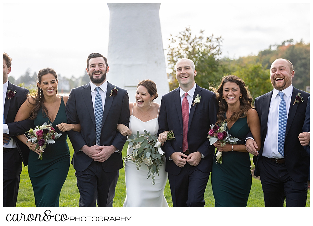 a bride and groom walk arm in arm with their bridal party on the lawn at The Nonantum Resort, Kennebunkport, Maine