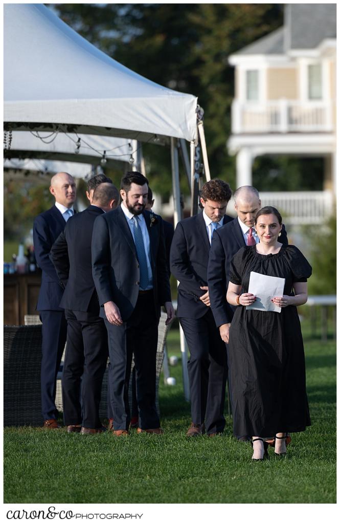 a wedding officiant leads a groom and groomsmen down the aisle at an outdoor wedding ceremony at The Nonantum Resort Kennebunkport Maine wedding