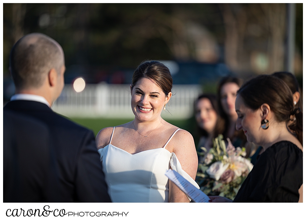 a bride smiles at her groom during an outdoor Nonantum Resort Kennebunkport Maine wedding ceremony