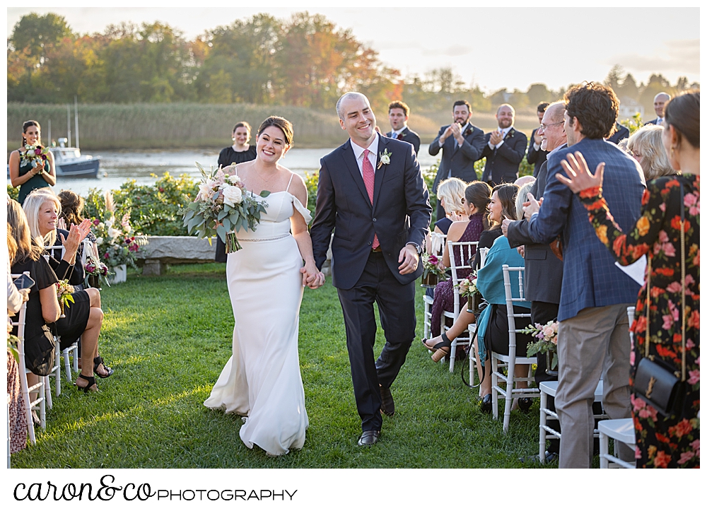 a bride and groom smile as they walk down the aisle during their Nonantum Resort Kennebunkport Maine wedding ceremony recessional