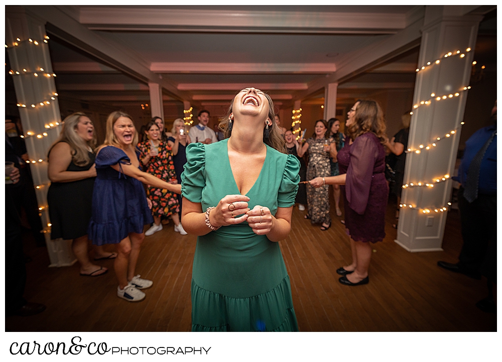 a woman in a green v-neck dress, her head thrown back, dances at a Nonantum Resort Kennebunkport Maine wedding reception