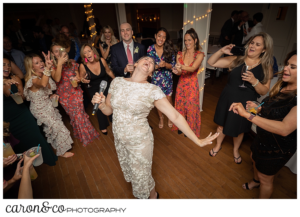 a bride, microphone in hand, head thrown back, dances and sings at a Nonantum Resort Kennebunkport Maine wedding reception