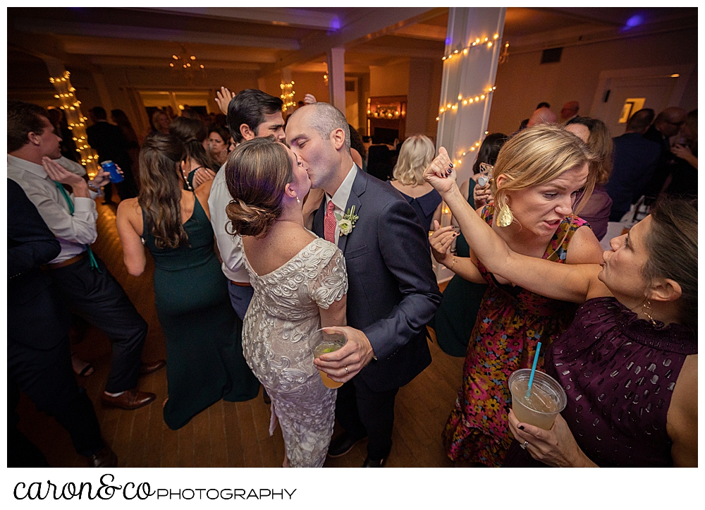 a bride and groom kiss while their guests dance around them at a Nonantum Resort Kennebunkport Maine wedding reception