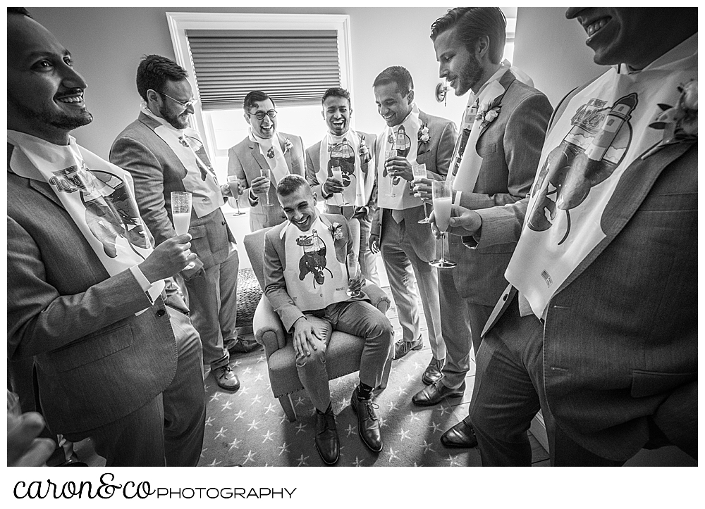 a black and white photo of a groom and several groomsmen wearing lobster bibs