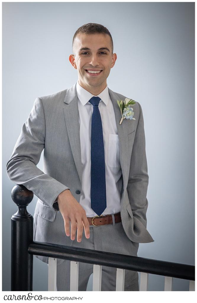 a groom, dressed in a gray suit, smiles during a portrait session