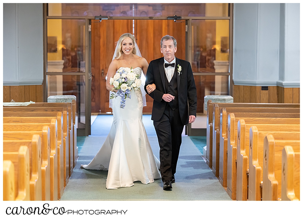 a man in a black suit, walks his daughter down the aisle of the St. Joseph's Church in Biddeford Maine