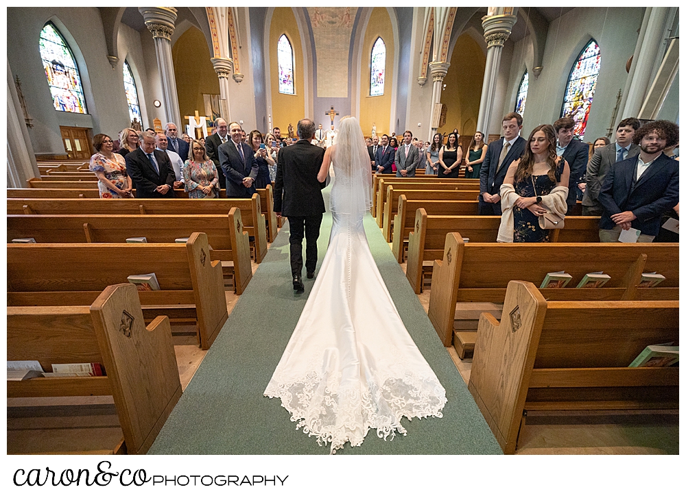 the back view of a bride and her father walking down the aisle at St. Joseph's Church in Biddeford, Maine