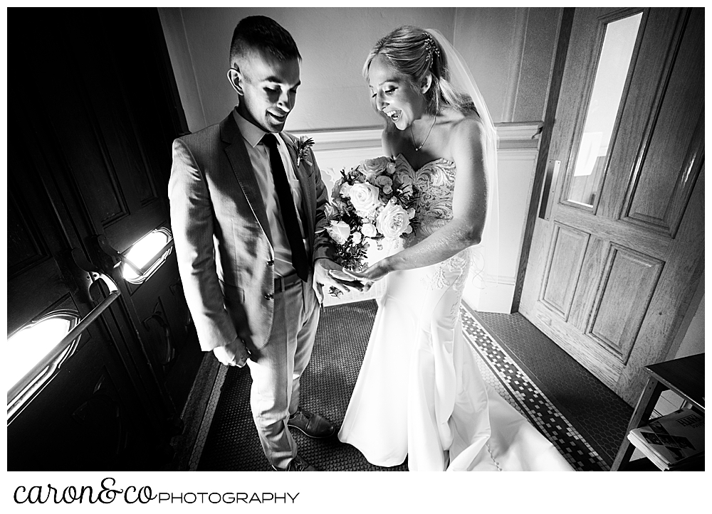 a black and white photo of a bride and groom looking at their wedding bands