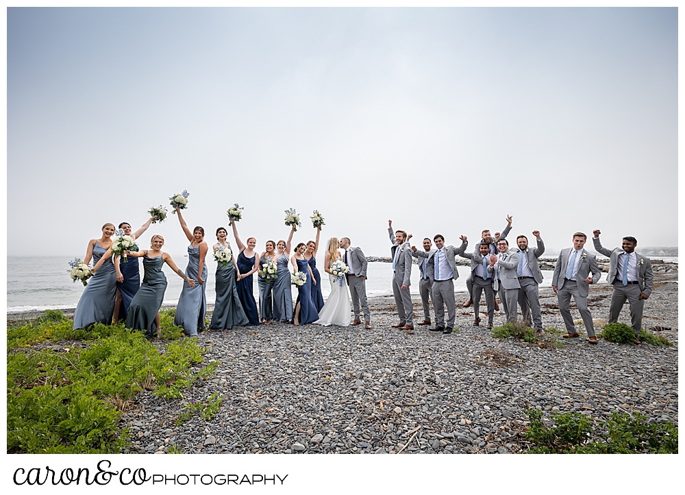 a huge wedding party cheers as a bride and groom kiss on Colony Beach, Kennebunkport Maine