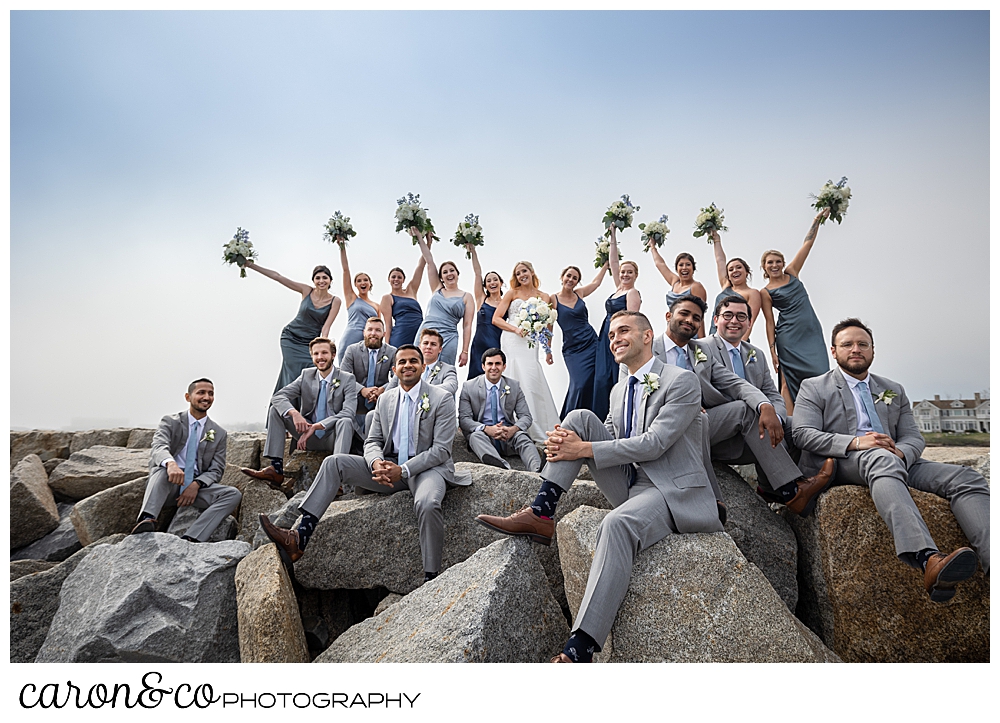 a wedding party mix it up by the guys sitting in front, and the ladies standing and cheering in back at the Kennebunkport Breakwater at Colony Beach, Kennebunkport Maine