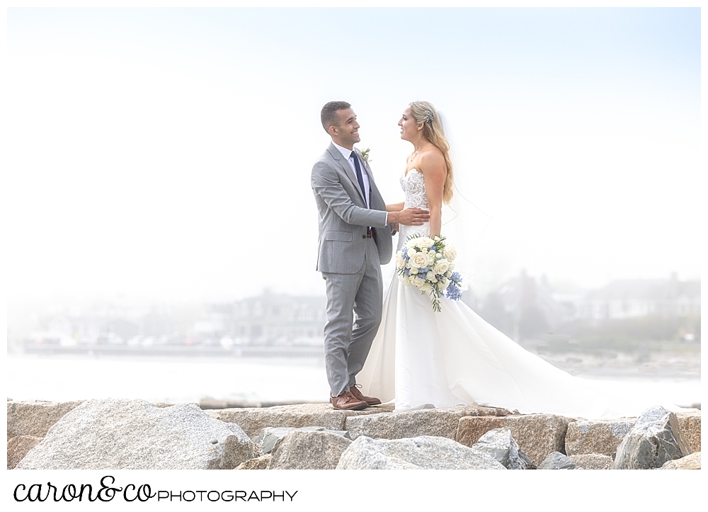a bride and groom stand facing each other on top of the Breakwater at Colony Beach, Kennebunkport Maine