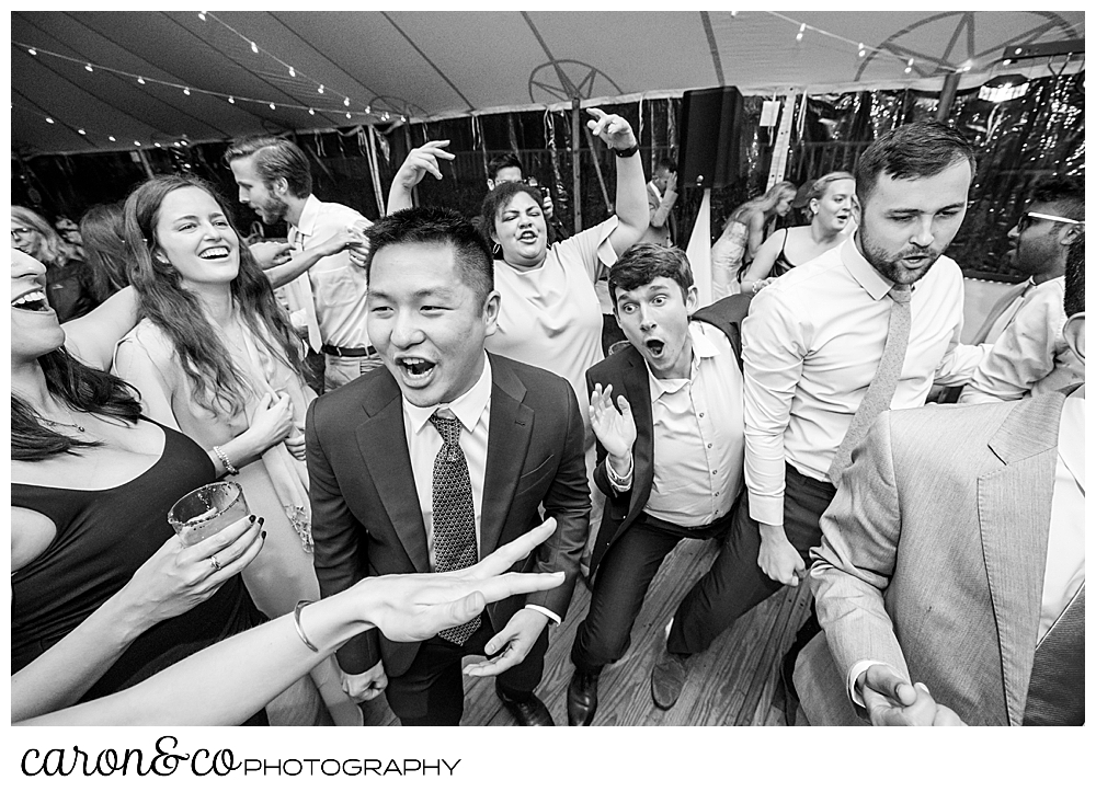 black and white photo of weddings guests singing, there's a hand in the foreground, pointing