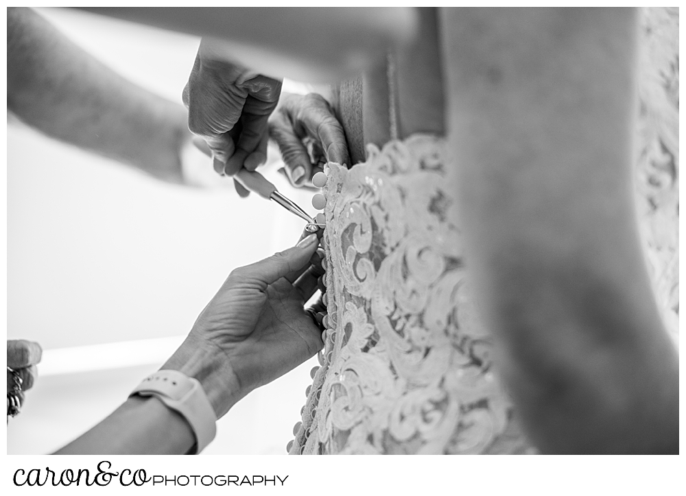 a black and white photo of buttons being fastened on a brides wedding dress