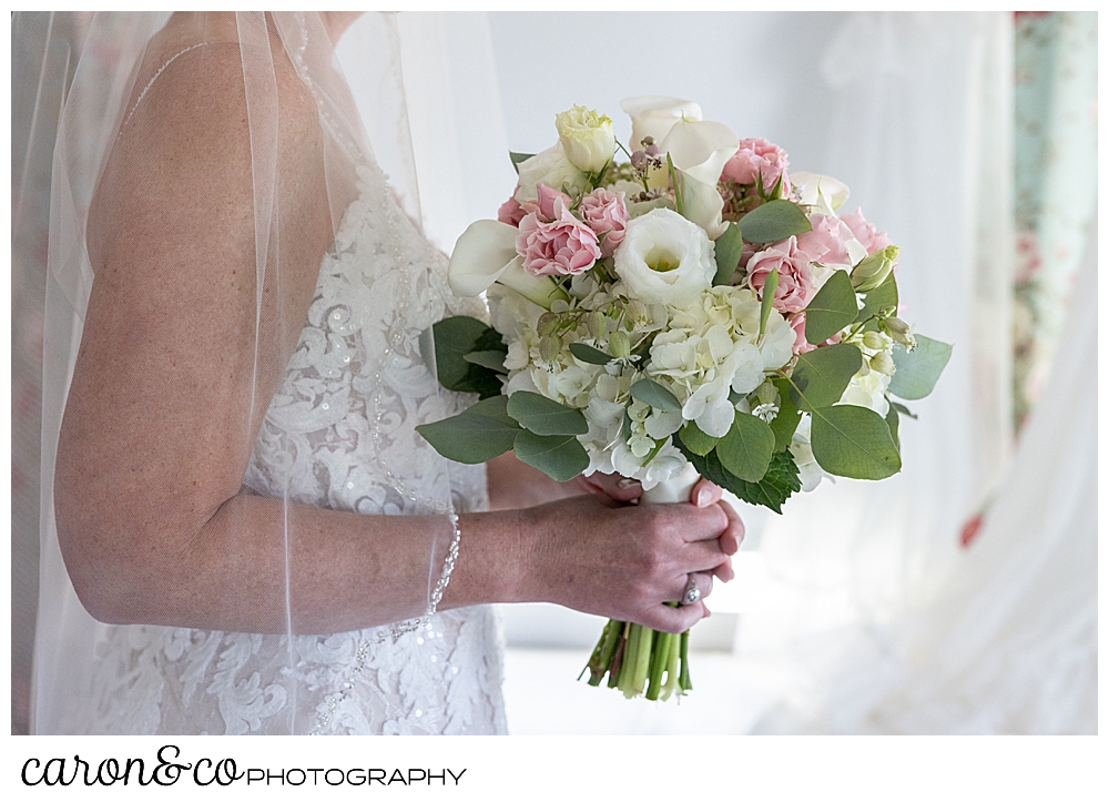 a bride holding a bridal bouquet of pink, white, and green